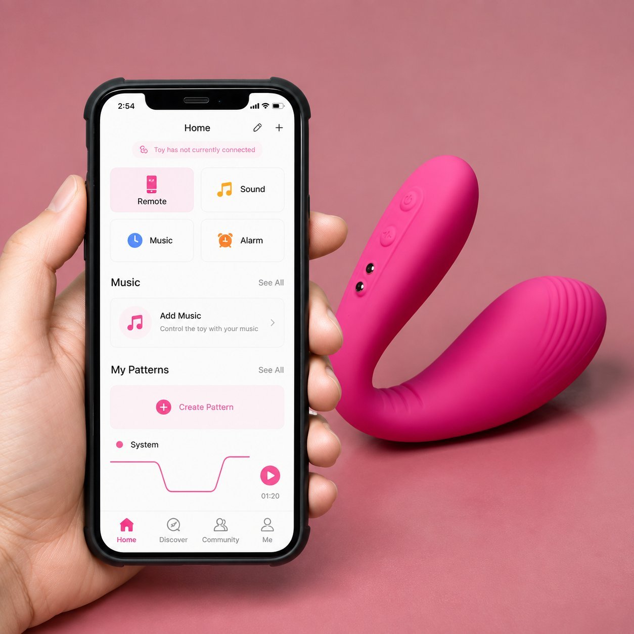 Pink C-shaped couples vibrator beside an iPhone showing a music-sync and pattern app home screen
